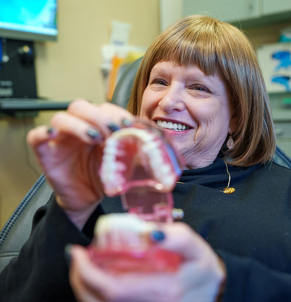 Patient holding a model of teeth
