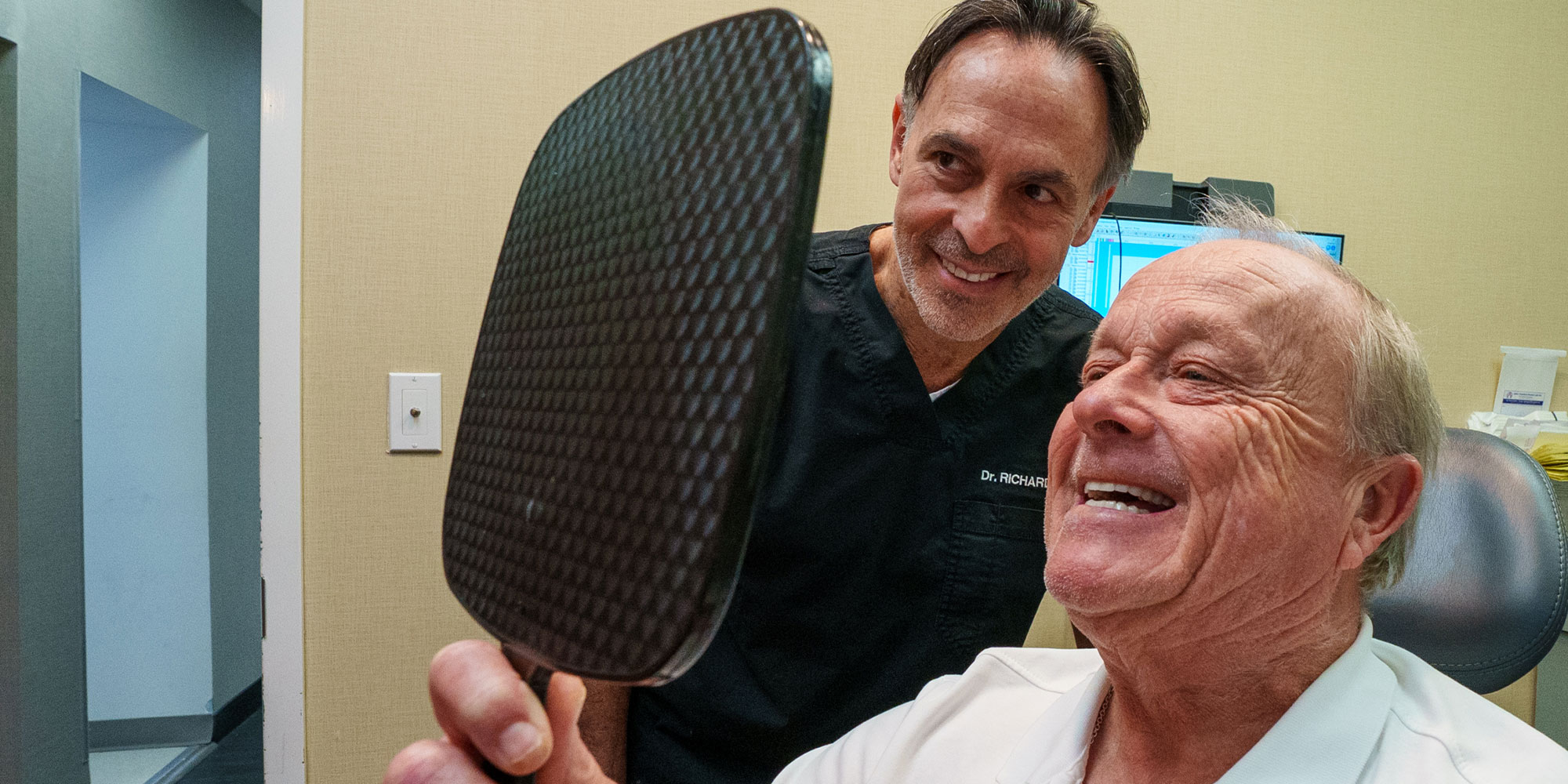 Patient and doctor looking into mirror smiling